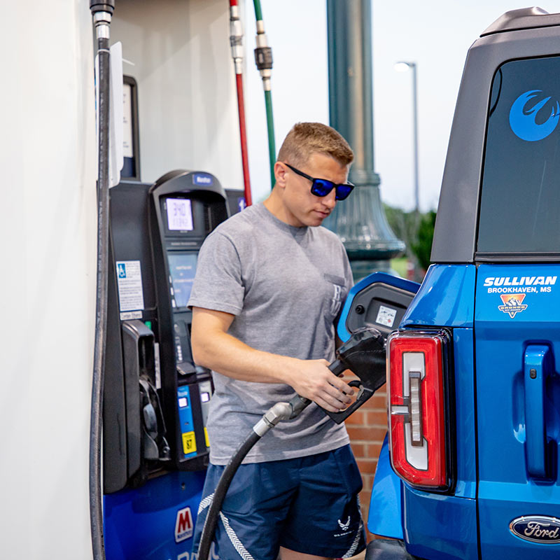 Man with sunglasses pumping gas